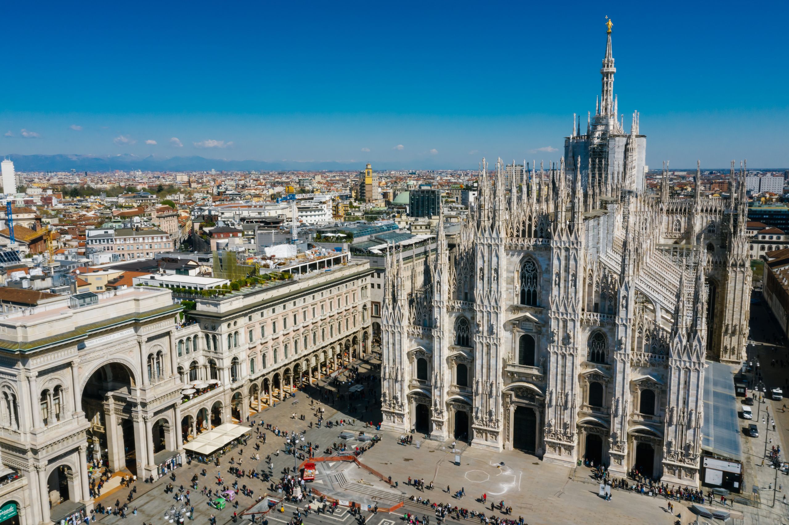 Stunning aerial shot of Milan Cathedral in Italy with bustling cityscape under a clear blue sky.