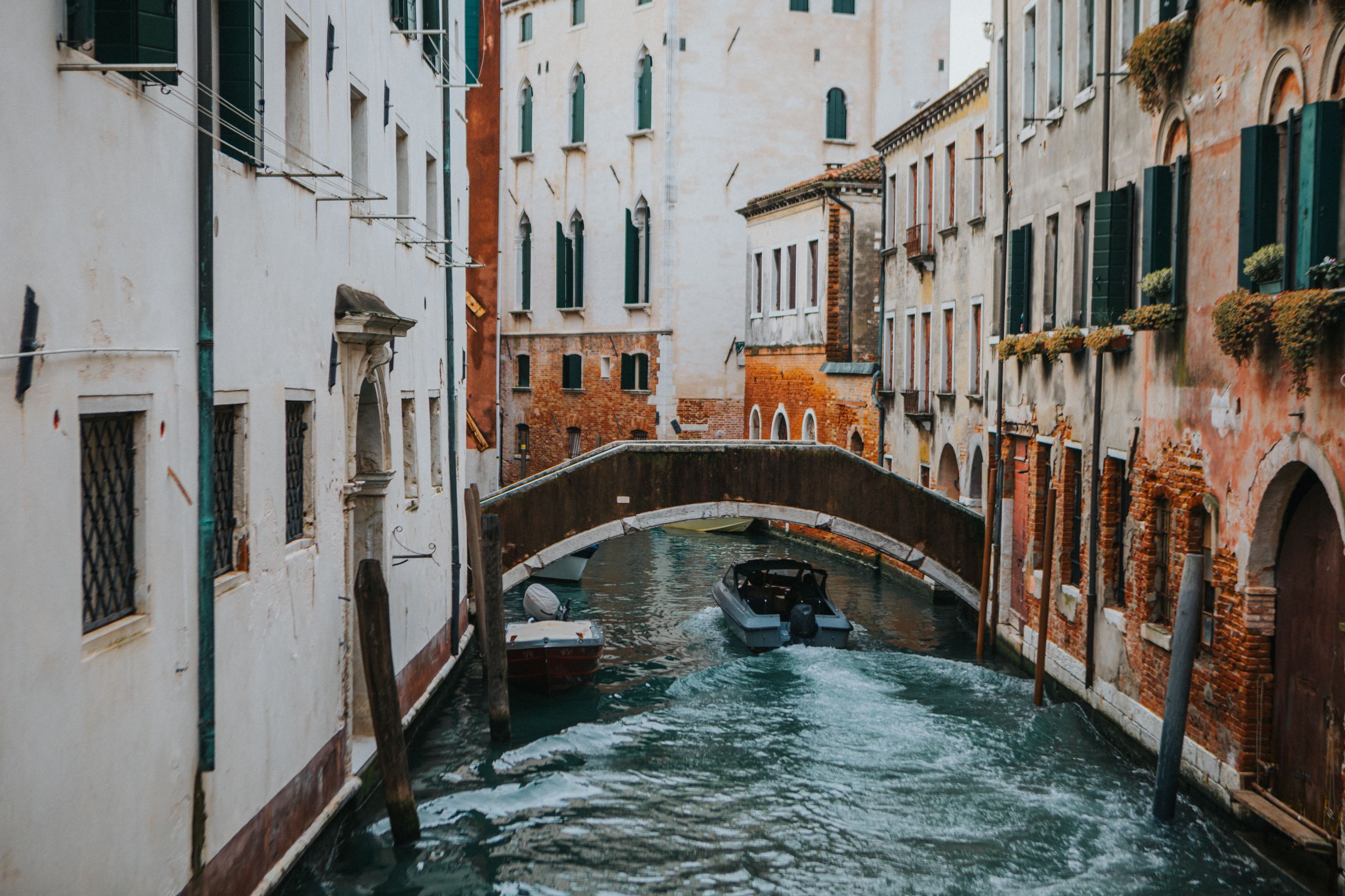 Charming Venetian canal with arched bridge and boats, showcasing classic Italian architecture.